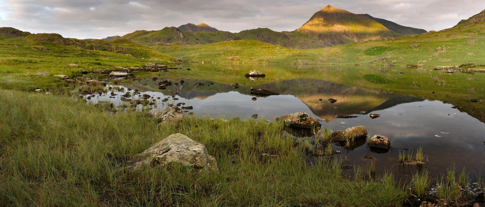 Sunlight shines on Crib Goch as it reflects in Llyn Cwmffynnon, Snowdonia. Image via Alamy