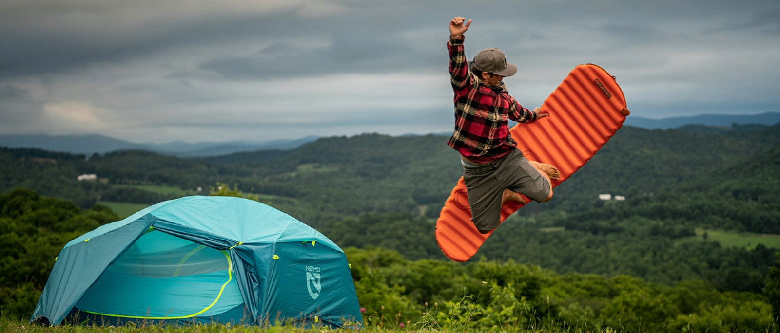 An orange Dark Energy Poseidon power bank resting on a topographic map inside a tent, with snow-capped mountains outside