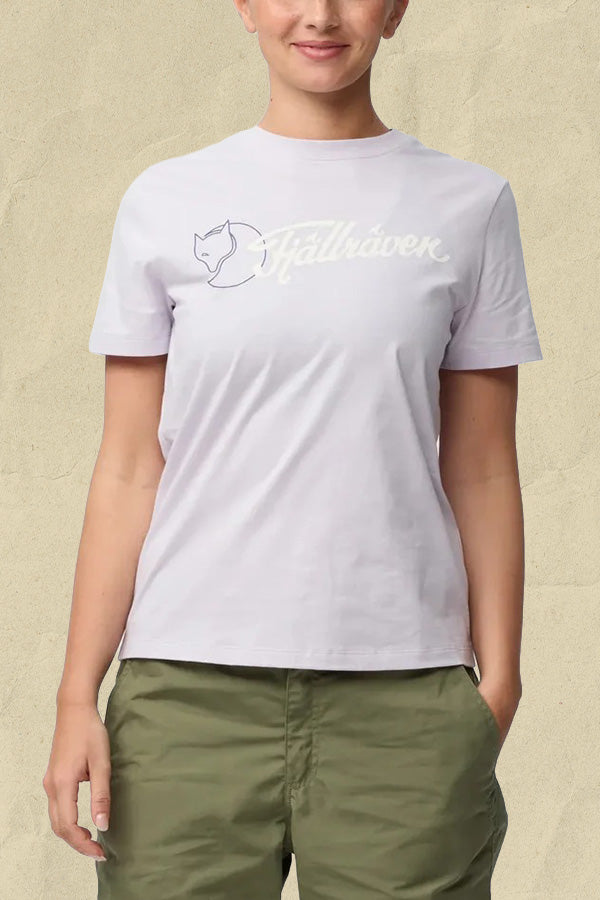 Woman wearing a lavender Fjällräven t-shirt with fox logo and text design, paired with olive green trousers.