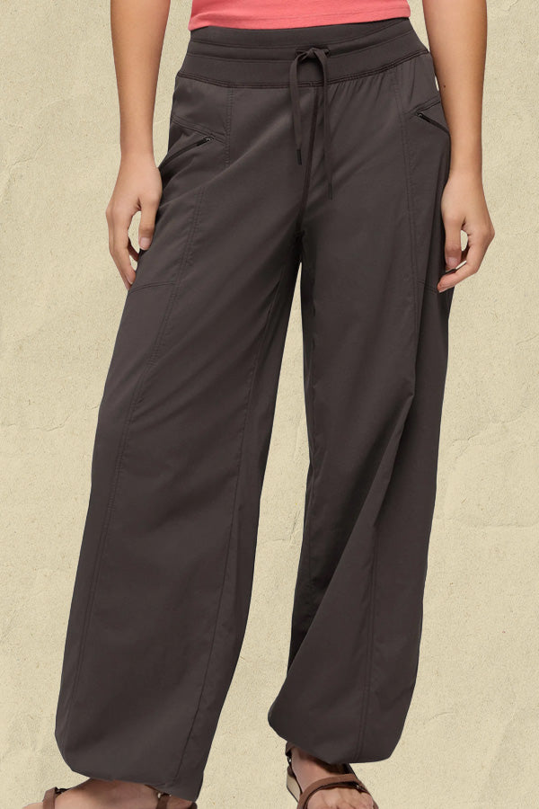 Woman wearing charcoal wide-leg trousers with drawstring waist and side pockets.