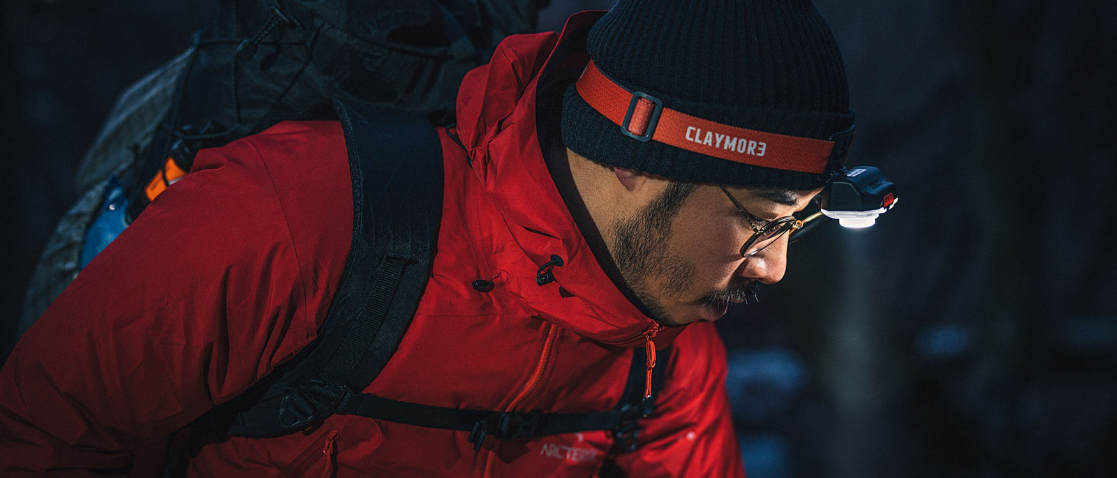 Night hiker navigating in dark woodland with headtorch angled downwards to offer a better view of the trail in front