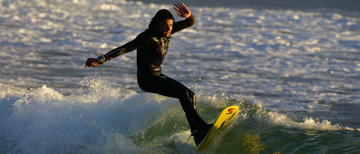 Surfer throwing spray off the top of a wave at golden hour, Whitesands Bay, Pembrokeshire