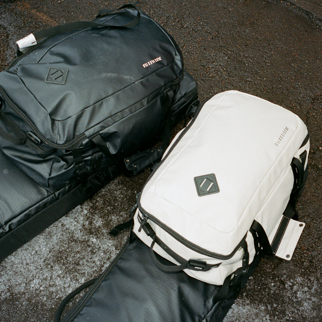 Herschel Supply Co. backpacks in black and white laid on concrete ground.