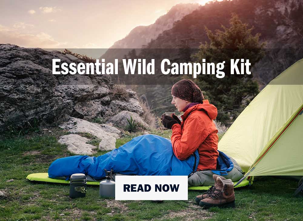woman wrapped in sleeping bag sitting on a mat infront of a tent